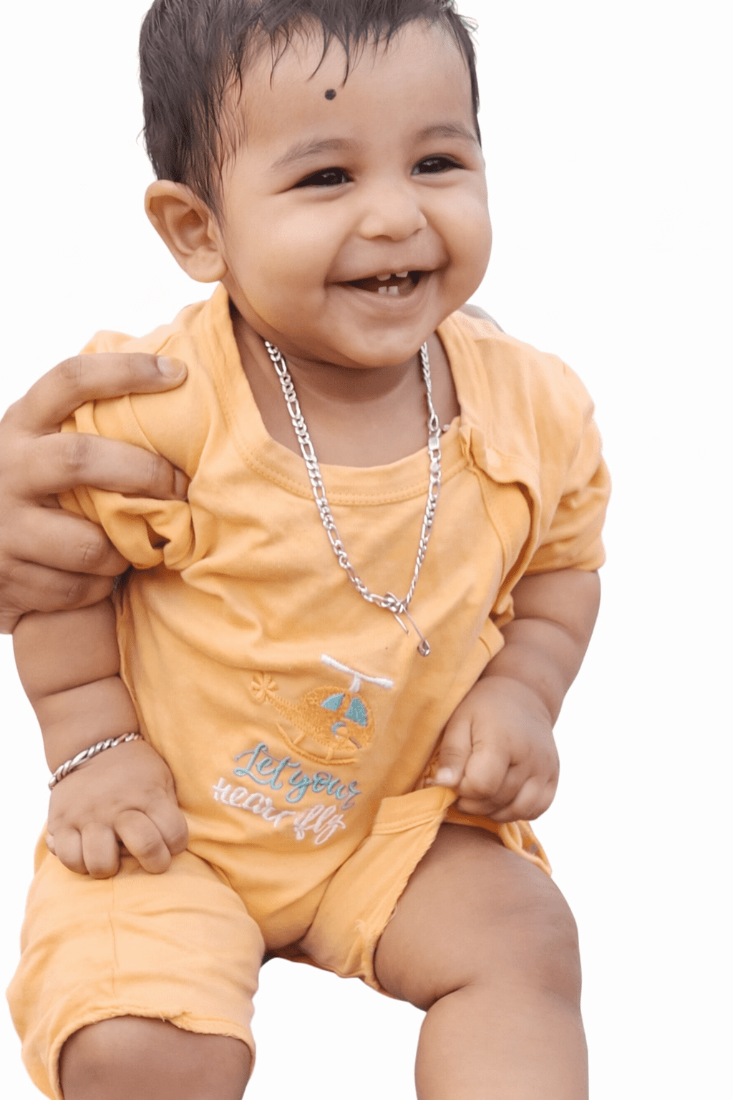 Baby in an orange outfit with a necklace on a white background